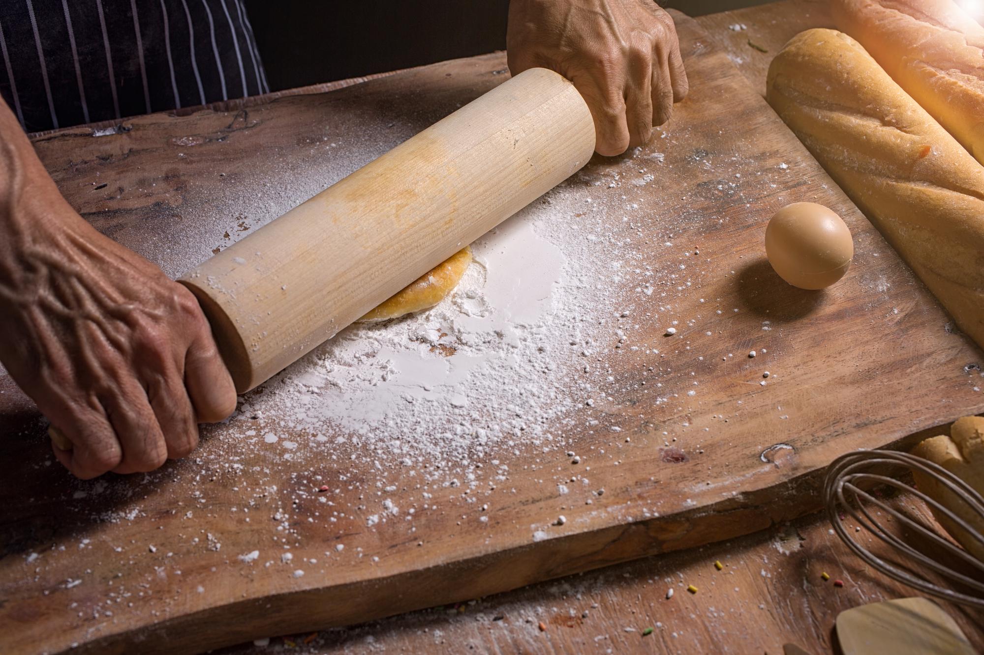 chef kneading dough on wooden board